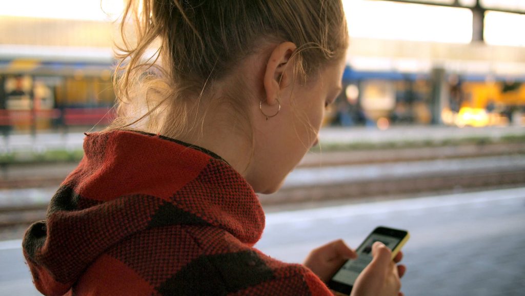 A woman waiting a train looking at her phone